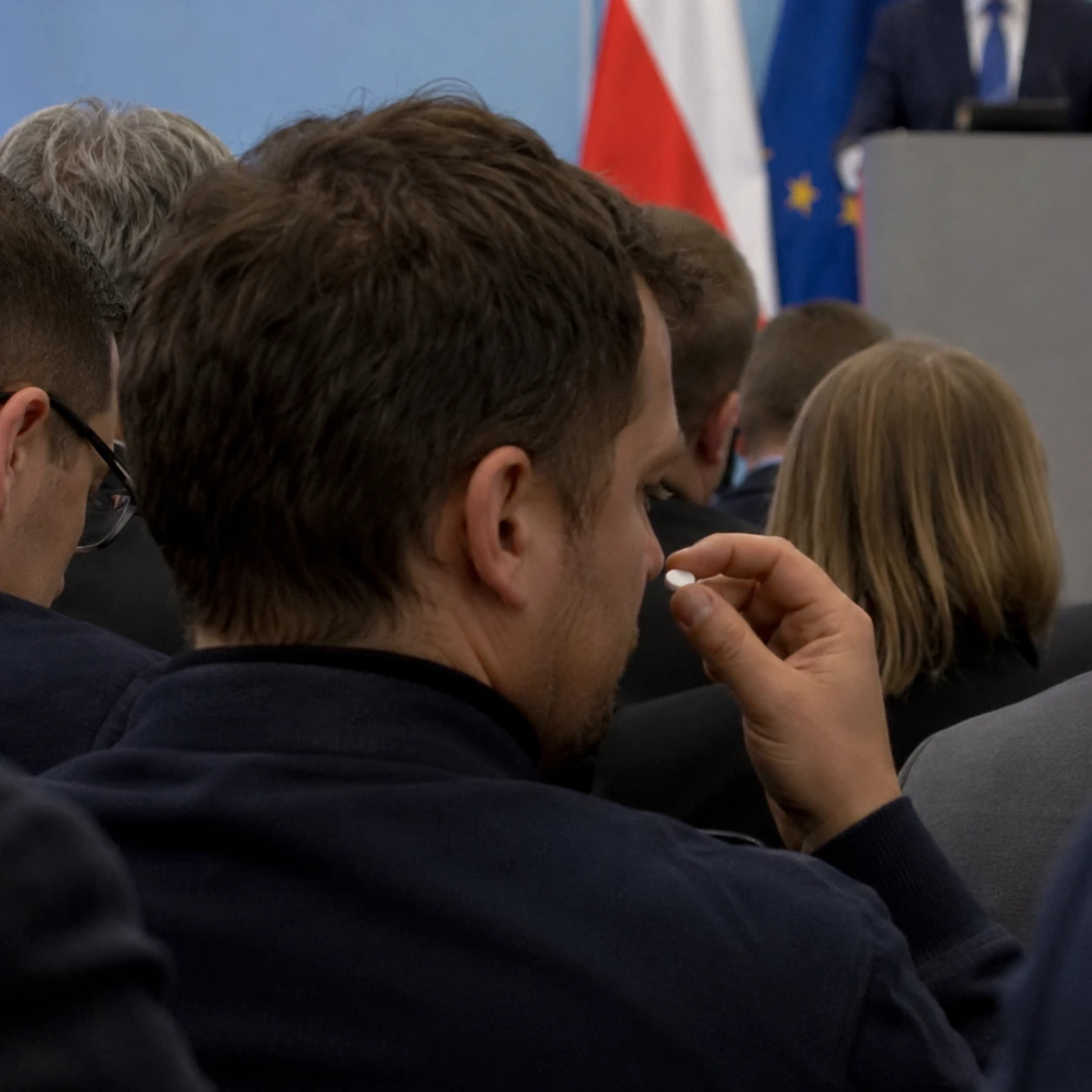 Uczestnik wydarzenia dyskretnie używa tabletki ODT na sali konferencyjnej.